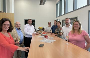 Group of people standing around table having a celebration. 